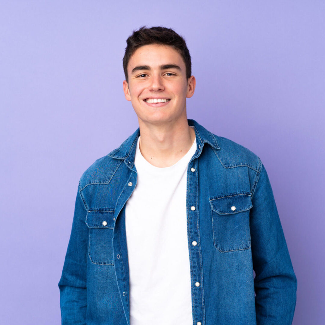 A man in blue jacket standing on top of purple wall.